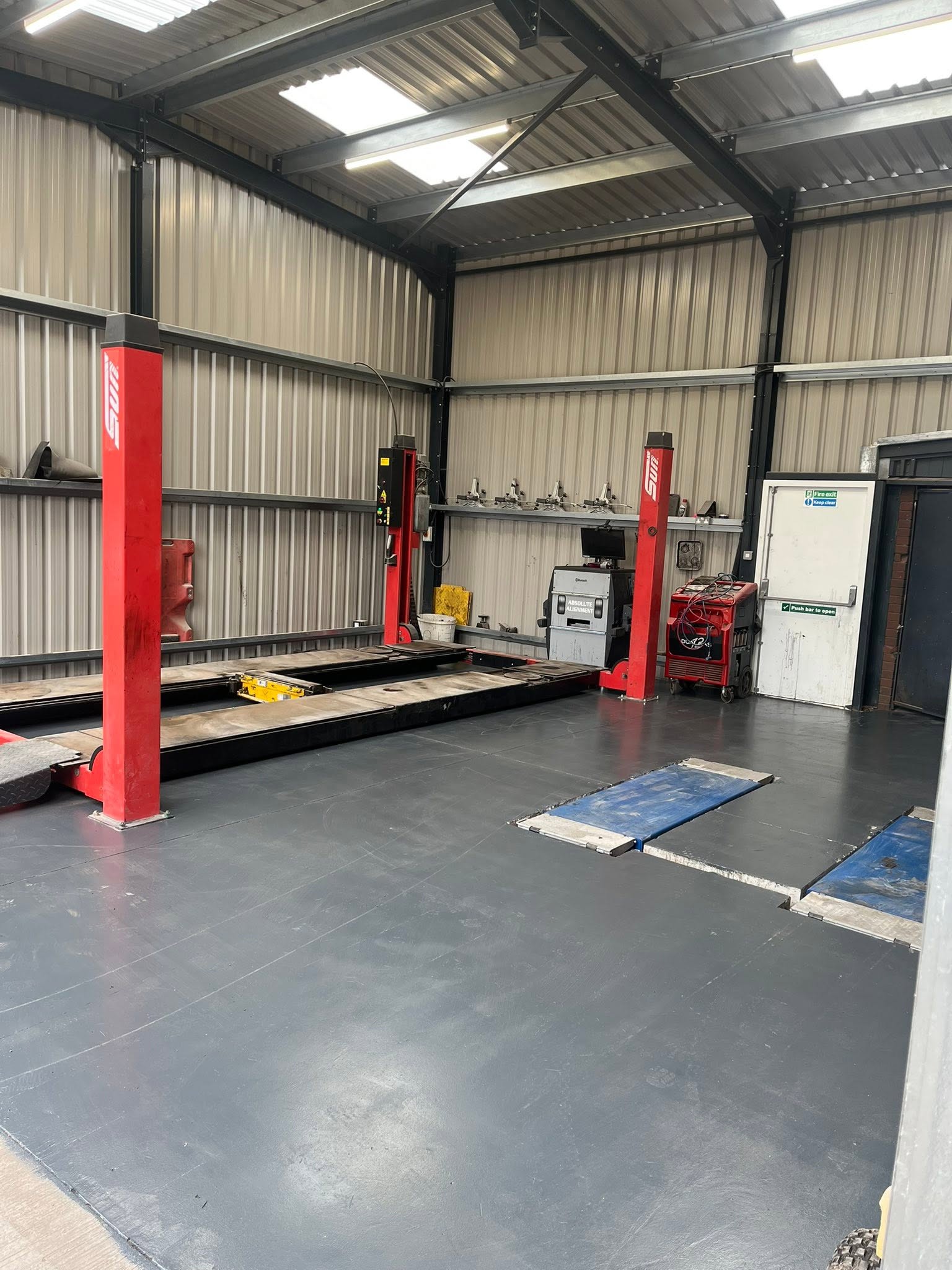 Red two-post lifts in a clad workshop bay